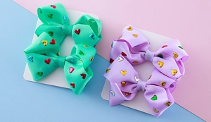 Detail of mint green and lavender grosgrain ribbon hair bows with colorful metallic hearts