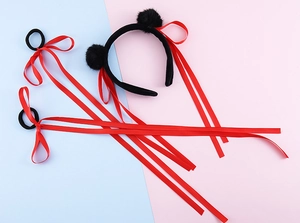 Dettaglio di nastri di raso rossi e pompon di peluche neri per accessori per capelli