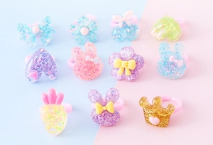Primo piano di anelli in resina glitterata per bambini con forme di coniglietti e corone