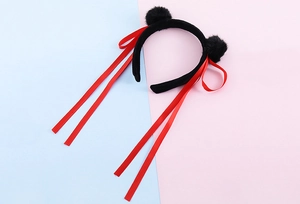 Dettaglio del cerchietto in peluche nero con pompon e lunghi nastri di raso rosso