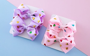 Detail of pink and purple grosgrain hair bows with metallic heart print on display card