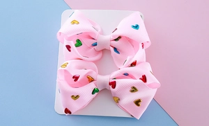 Macro view of pink ribbed bows with colorful metallic heart patterns on display card