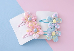 Close-up of four floral hair clips with sequins and pearls in pink and blue colors