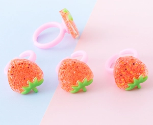Dettaglio di quattro anelli fragola in resina glitterata con fasce rosa regolabili per bimbe