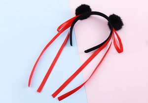 Dettaglio di un cerchietto con pompon neri e lunghi nastri in raso rosso per il cosplay