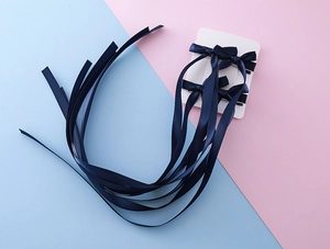 Détail de quatre barrettes à nœuds en satin bleu marine avec de longs rubans pendants