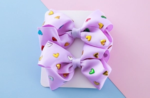 Detailed macro shot of lavender grosgrain hair bows with colorful metallic heart sequins