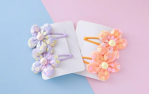 Detail of sequin floral hair clips with pearl centers on pastel card packaging