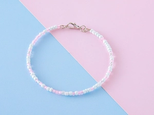 Détail du bracelet en perles roses et blanches avec un fermoir mousqueton argenté élégant