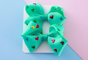Detail of mint green hair bows with metallic heart patterns on display card