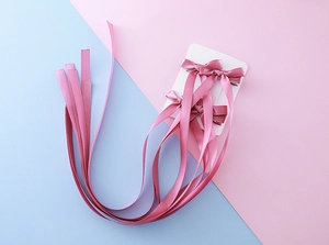 Vue détaillée de barrettes à nœuds en satin rose avec longs rubans sur carte blanche