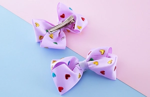 Detail of purple ribbed ribbon hair clips with colorful metallic heart sequins for girls