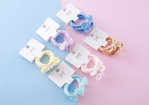 Detail showing set of six colorful bow hair ties on display card with soft macaron colors