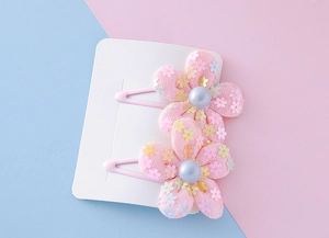 Detail of pink mesh flower hair clips with sequins and pearls on a white card display
