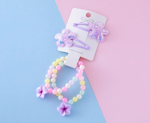 Détail de bracelets en perles macaron et barrettes fleur à paillettes mauves pour filles