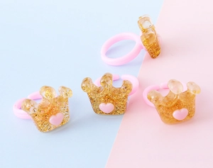 Dettaglio macro di anelli rosa regolabili per bambini con corone di resina glitter