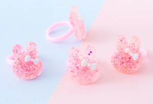 Dettaglio di anelli per bambini a forma di coniglio in resina rosa con brillantini