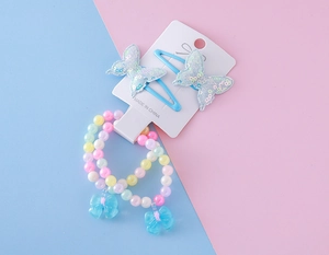 Détail de bracelets en perles macaron avec breloques nœud et pinces papillon bleues à paillettes
