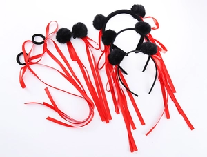 Dettaglio di accessori per capelli con nastri rossi e pon pon neri per feste