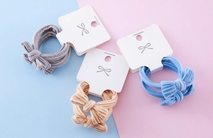 Detail of colorful bow hair ties on card with striped fabric texture and elastic design