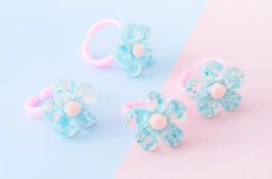 Dettaglio di quattro anelli di plastica rosa con fiori in resina blu e glitter colorati