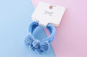 Close-up of blue bow hair tie made of elastic towel fabric on white display card