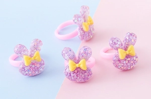 Dettaglio di anelli rosa per bambini con orecchie di coniglio glitterate e fiocchi gialli
