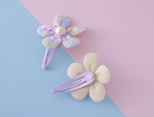 Detailed view of sequin flower hair clips with pearl beads and purple snap closure