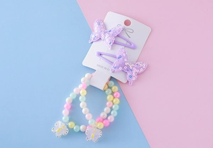 Détail des pinces à cheveux papillon pailletées violettes et bracelets de perles pour filles