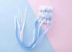 Vue détaillée de quatre barrettes à longs rubans bleu clair sur support carton blanc
