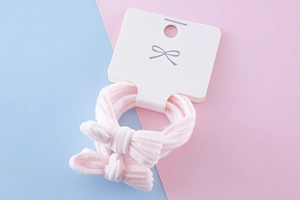 Close-up of pink bow hair ties on display card with soft pastel fabric texture