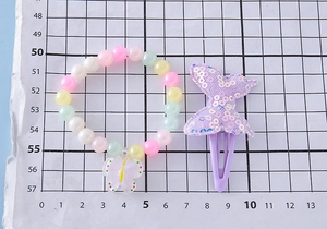 Détail du bracelet de perles colorées pour enfants avec pendentif et pince papillon à paillettes