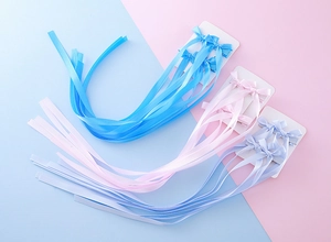 Détail des barrettes à nœuds en satin avec de longs rubans en bleu, rose et violet clair