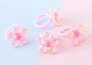 Dettaglio di quattro anelli a fiore per bambini in plastica rosa con glitter in resina