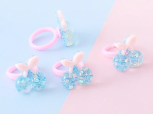 Dettaglio di quattro anelli in resina rosa con ciliegie blu trasparenti e glitter colorati