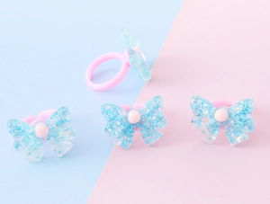 Dettaglio di quattro anelli a fiocco in resina per bambini con paillettes colorate