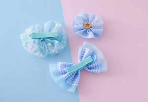 Détail de pinces à cheveux bleues avec nœuds en résille et motifs vichy pour filles