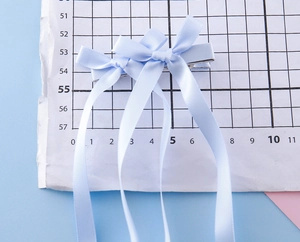 Détail de barrettes à nœuds bleu clair avec longs glands montrant les dimensions réelles
