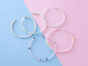Detail of five colorful handmade beaded rings in pastel macaron shades with small metal clasps