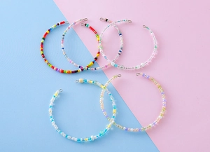 Detailed view of colorful handmade seed bead hoop earrings in five vibrant summer styles