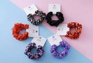 Flat lay detail of six Halloween scrunchies with sequins and ghost prints on card
