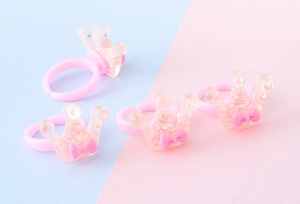 Dettaglio di anelli a corona rosa glitterati in resina con fiocchi per bimbi