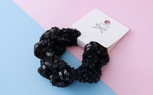 Close-up of black sequined Halloween scrunchie with sparkling mesh on a display card