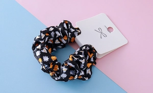 Detail of black Halloween scrunchie featuring ghost and pumpkin prints on satin fabric