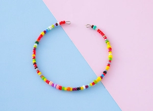 Close-up of colorful handmade seed bead necklace with silver clasps on pastel background