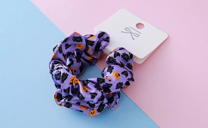 Detailed view of Halloween scrunchie with pumpkin and spider prints on purple satin
