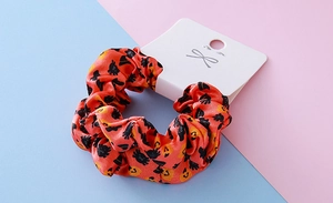 Detailed view of orange satin Halloween scrunchie with black spider and pumpkin prints