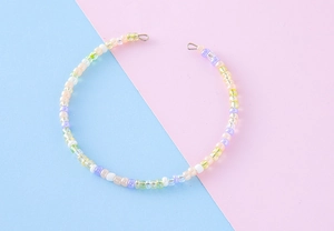 Detailed view of handmade colorful rice bead chain in pastel tones on pink blue background
