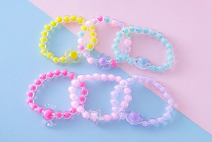 Detalle de pulseras de cuentas acrílicas de colores con colgantes de corazón, flor y estrella