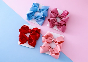 Détail de 8 pinces à cheveux aux couleurs bonbon avec un design soigné de nœud double couche